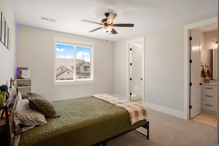 Carpeted room featuring a ceiling fan with integrated lighting, a window with exterior views, and a white paneled door