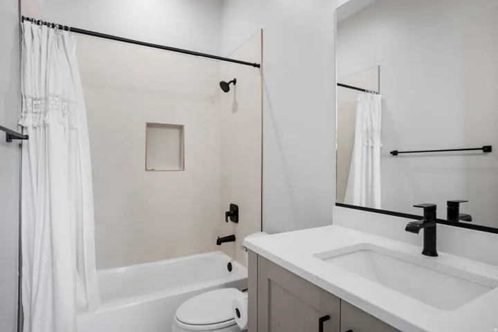 White tile surround with recessed shelf and matte black shower fixtures