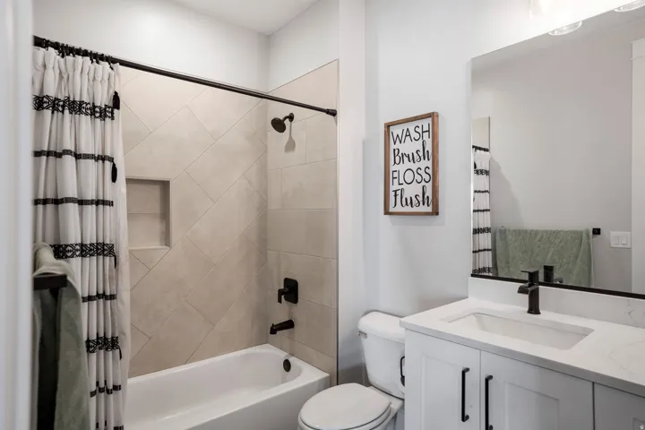 Bathroom featuring a white vanity with a rectangular undermount sink and matte black faucet, a framed mirror, and a white toilet