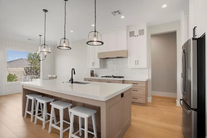 Kitchen featuring a large central island with solid surface countertop, stainless steel appliances, white subway tile backsplash, and light wood-finish flooring