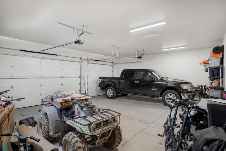 Spacious garage with multiple overhead garage doors, concrete flooring, overhead lighting, and white walls