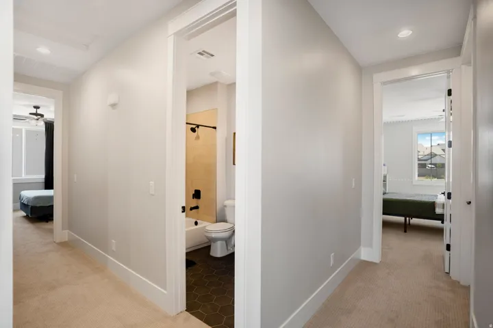 Hallway with light gray walls, white trim, and neutral carpet flooring