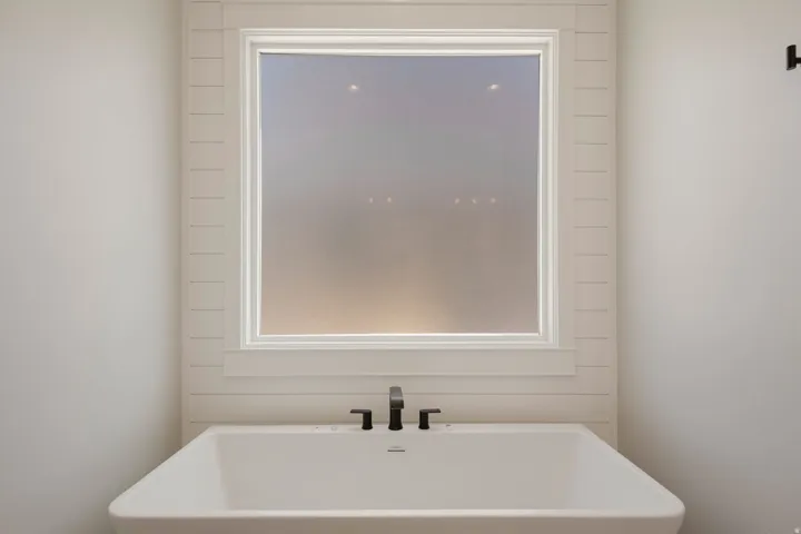 Freestanding soaking tub with a matte black deck-mounted faucet and hand shower