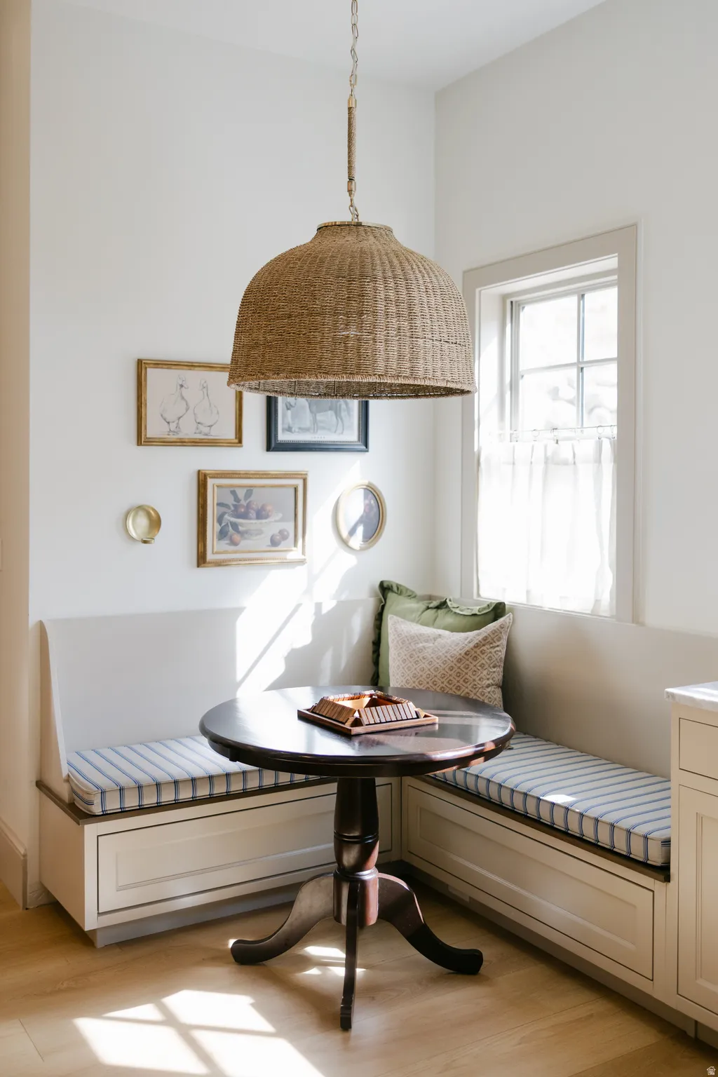 Built-in banquette seating with storage beneath, wood-finish flooring, and a woven pendant light fixture
