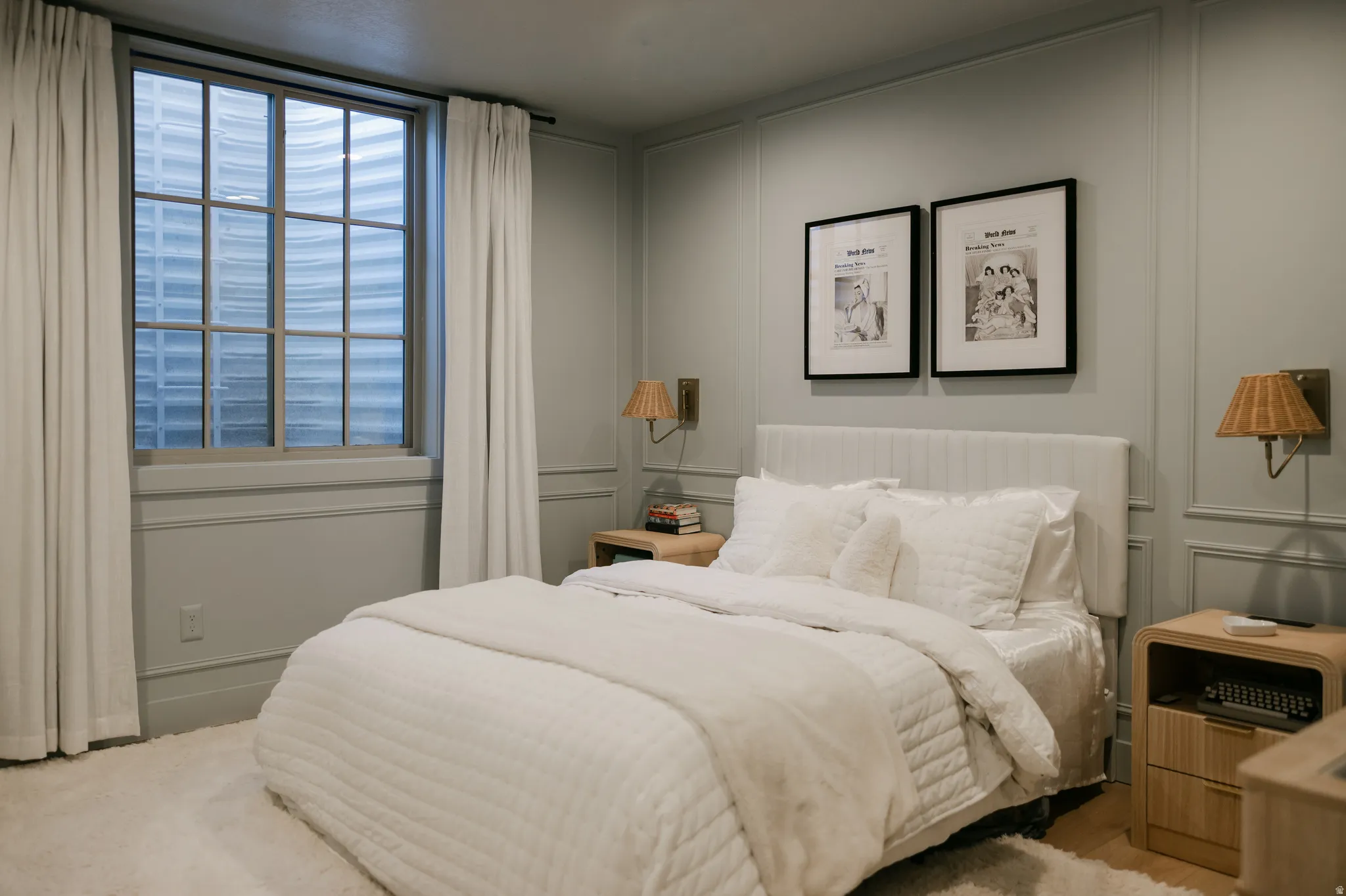 Wall paneling, built-in wall sconces, window with gridded panes, upholstered headboard, and wood-finish nightstands