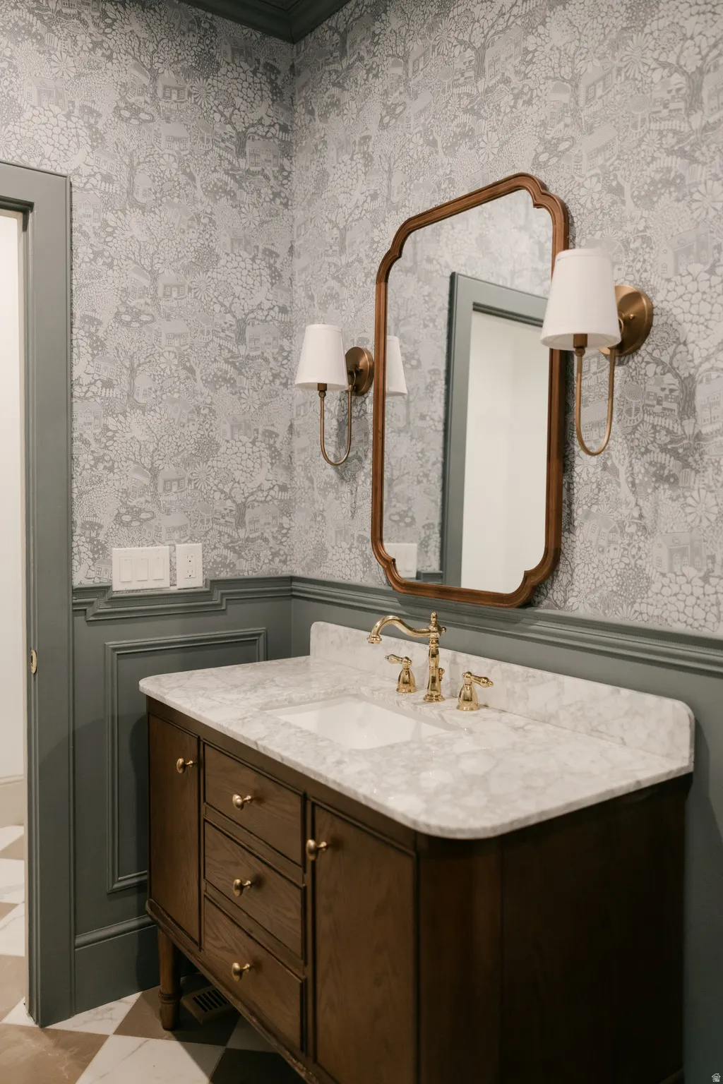 Wood-finish vanity with an integrated sink, polished brass faucet, and a light-toned countertop