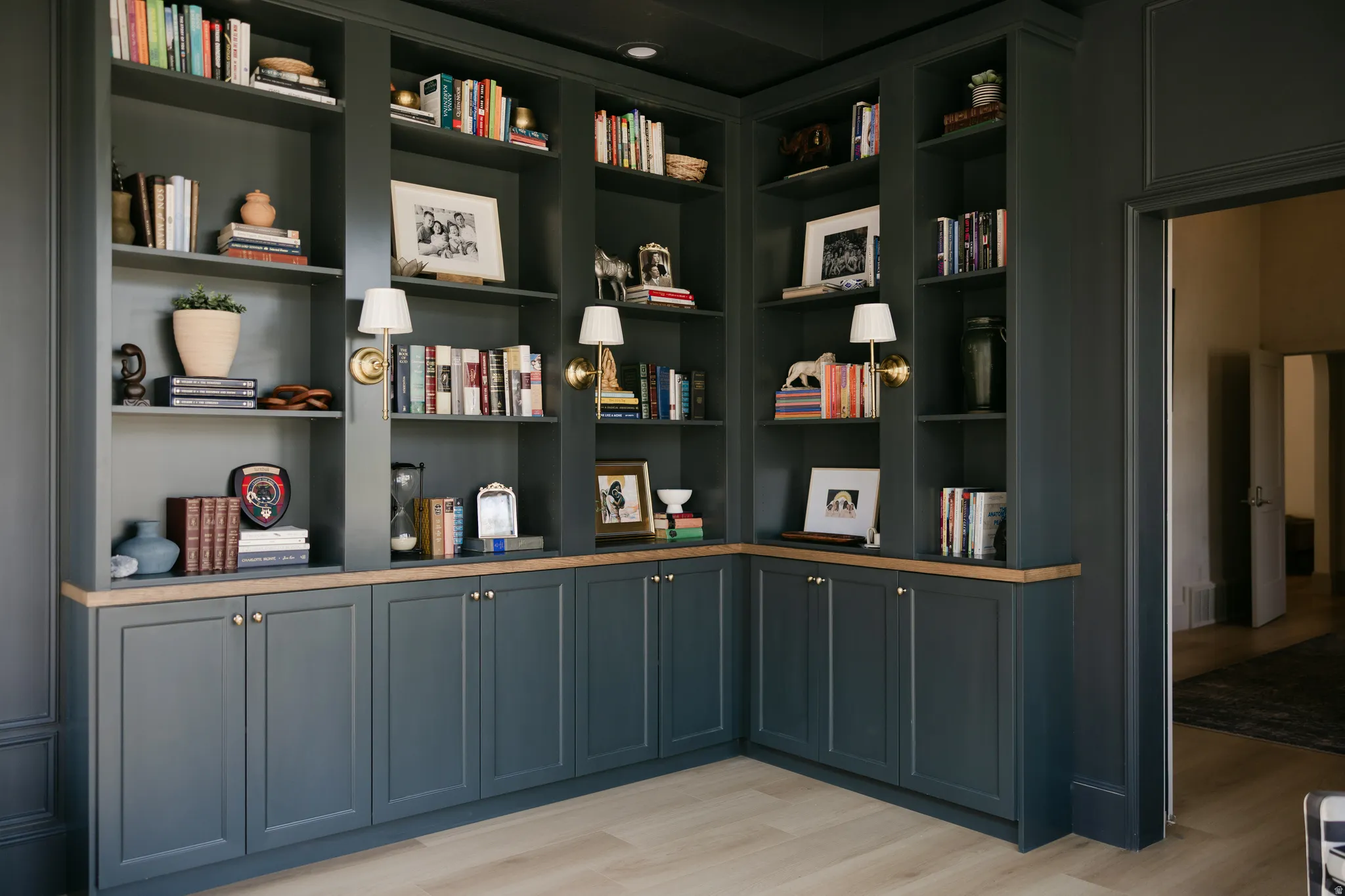 Custom built-in shelving with integrated cabinetry, wood-finish countertops, and wall-mounted brass sconces