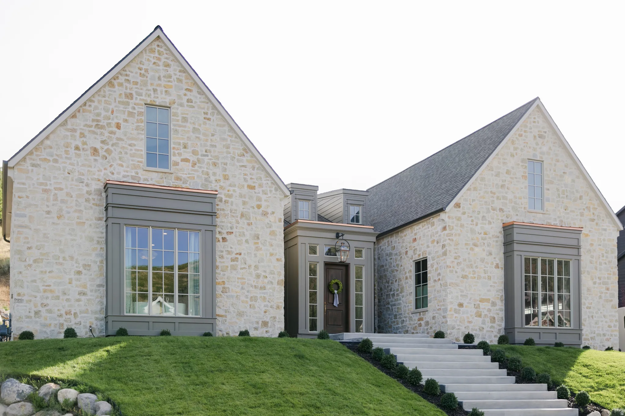 Stone facade with architectural gables, multi-pane windows, and a dark shingle roof