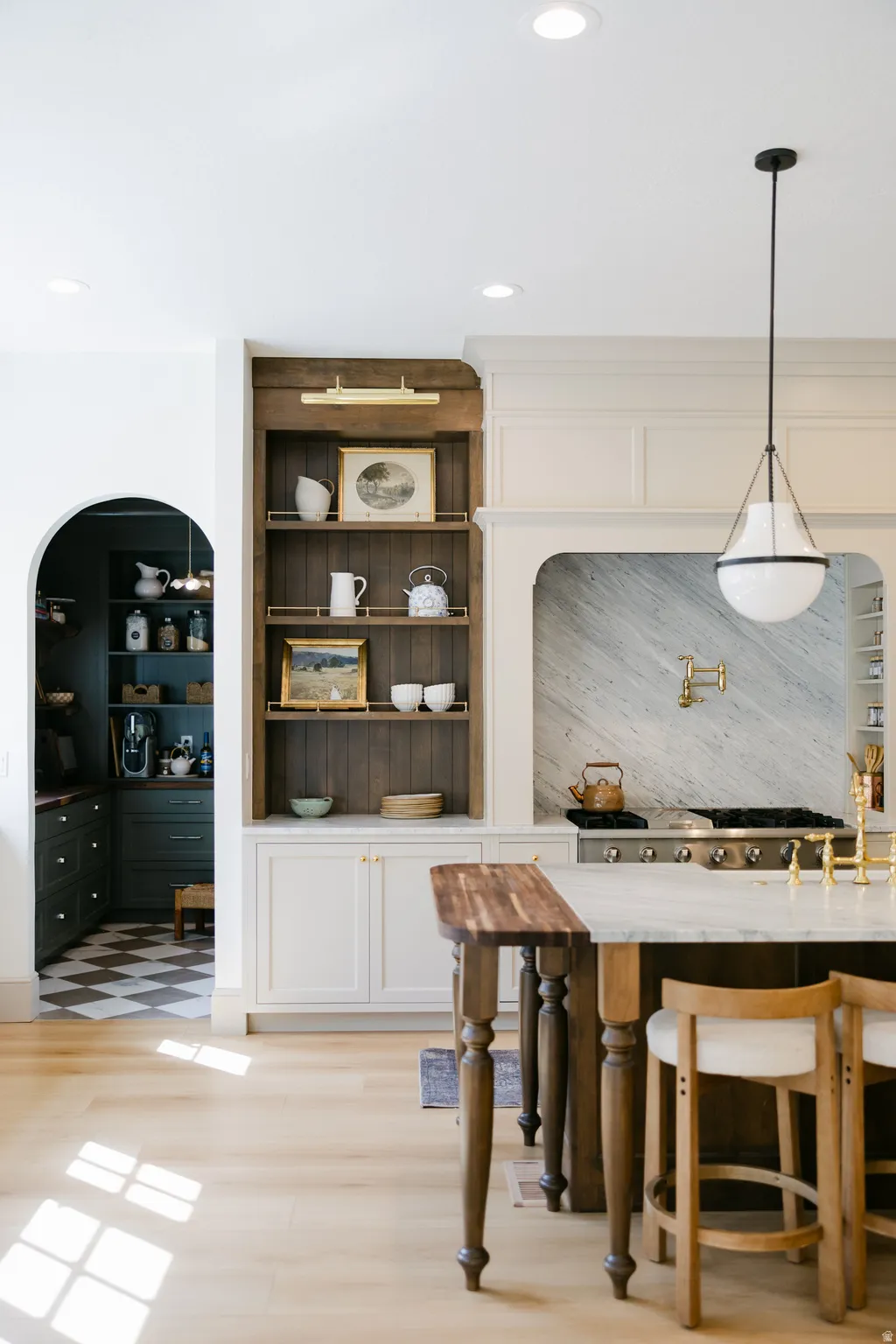 Recessed ceiling lighting, wood-finish flooring, built-in shelving, white cabinetry, and a kitchen island with seating