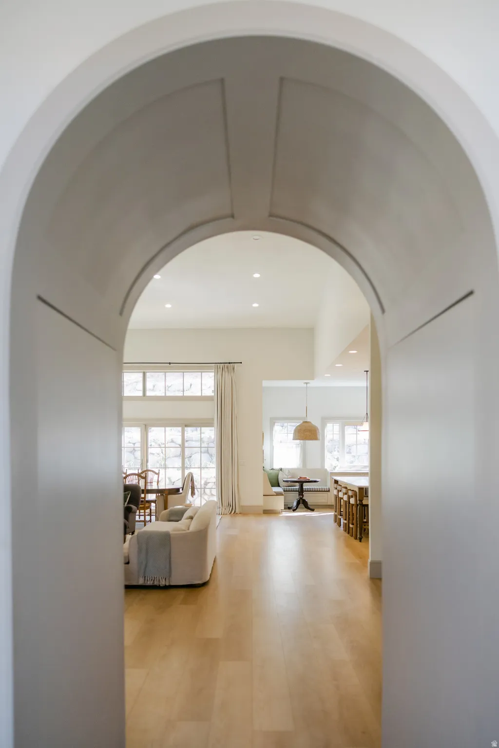 Archway entry with detailed millwork, wood-finish flooring, recessed lighting, and expansive windows
