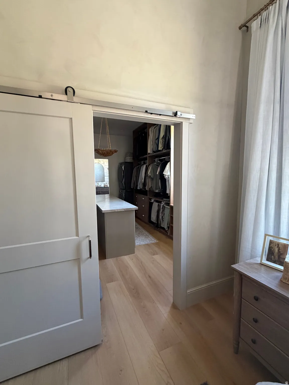 Barn door entry to a closet featuring wood-finish flooring and built-in shelving