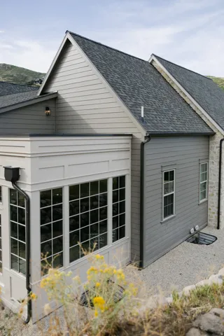 Gable roofline with dark shingles and light gray horizontal siding