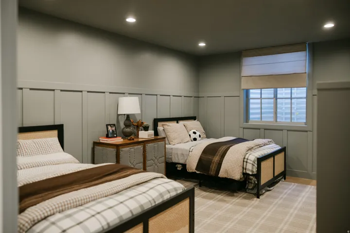 Board and batten wall treatment, recessed ceiling lighting, single window with roller shade, neutral tone wall color, and light-colored patterned carpeting