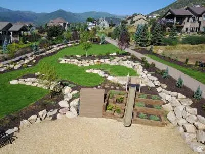 Terraced landscaping featuring natural rock retaining walls, a slide, and raised garden beds