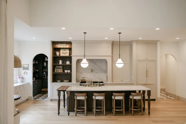 Kitchen featuring an expansive island with seating, integrated appliances, custom cabinetry, a statement range hood, and light wood-finish flooring