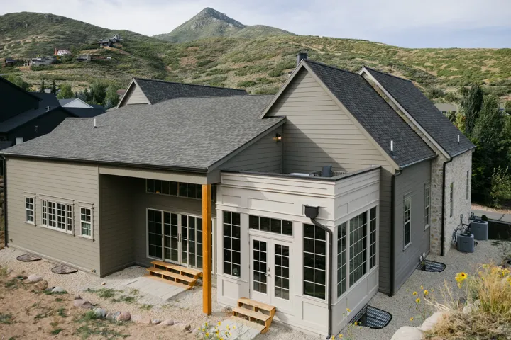 Multi-level exterior with a stone and siding facade, featuring a sunroom and extensive window placements