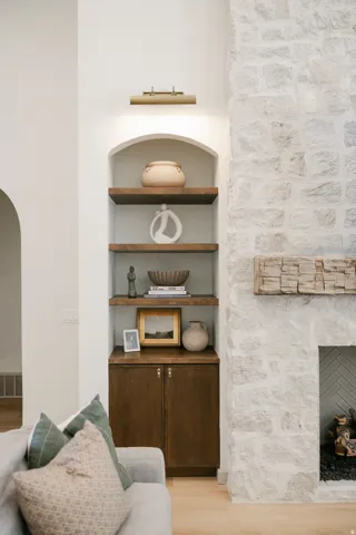 Arched built-in shelving with wood-finish shelves, warm wood-finish cabinetry, and an integrated picture light