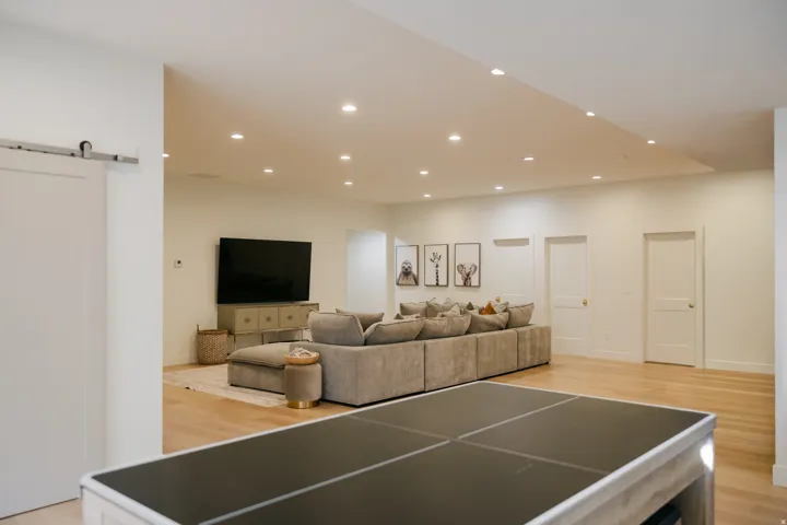 Recessed lighting, light wood-finish flooring, white walls, white doors, barn-style door hardware