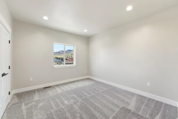 Recessed ceiling lighting illuminates the textured gray carpeting and white trim