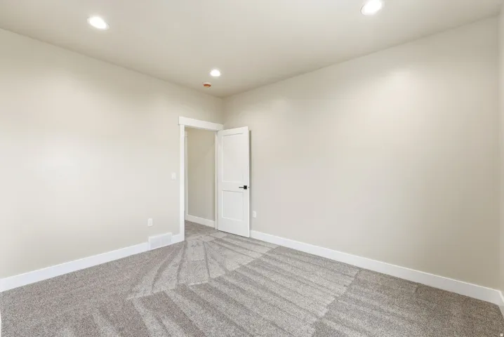 Recessed lighting, light gray carpet, white trim, and a white interior door with black hardware