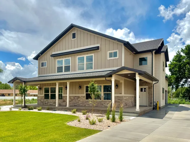 Two-story residence featuring vertical siding and stone veneer accents