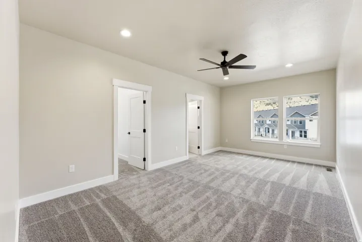 Spacious room featuring neutral carpet, light-colored walls, recessed lighting, a ceiling fan, and multiple windows