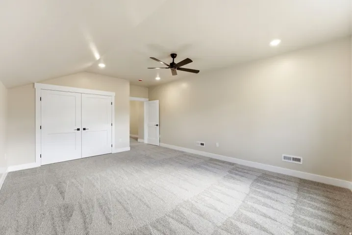 Spacious room featuring vaulted ceilings, recessed lighting, a ceiling fan, and light-toned carpeting