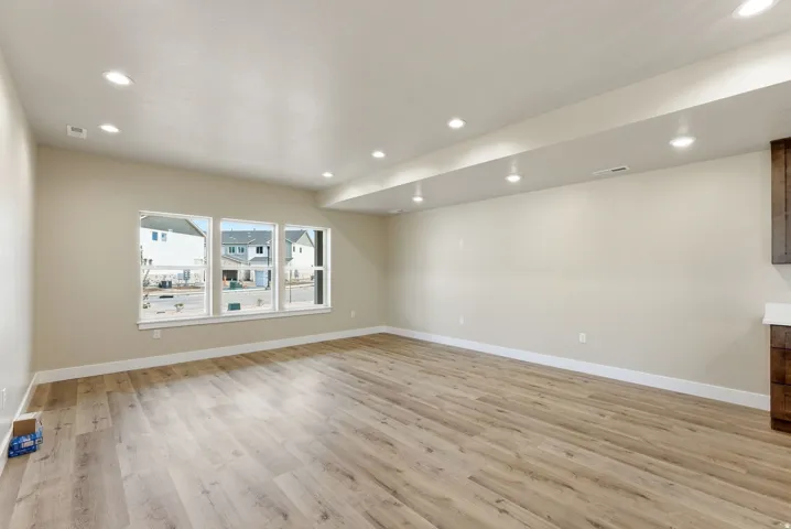 Recessed lighting, light-toned walls, wood-finish flooring, three large windows, and built-in cabinetry