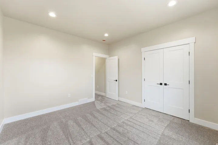 Recessed lighting, light-toned carpeting, white trim, and white paneled doors with dark hardware