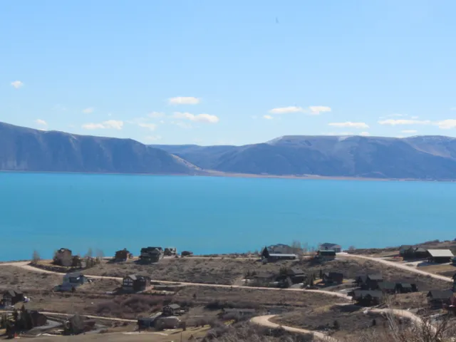 Expansive hillside setting with distant lake and mountain backdrop