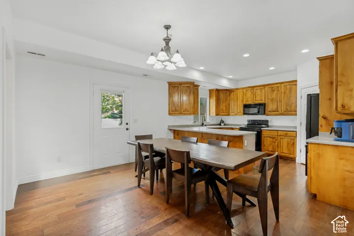 Wood-finish flooring throughout, with a built-in kitchen featuring wood cabinetry, stone countertops, and black appliances