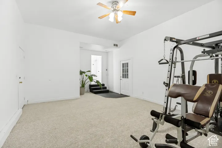 High ceiling with a ceiling fan, light-colored carpet, white walls, and a multi-pane door