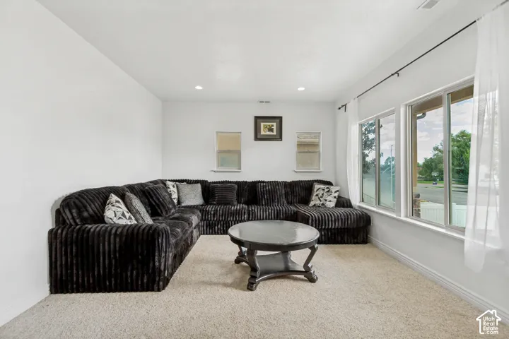Recessed lighting, light-colored carpeting, and a large window with white trim