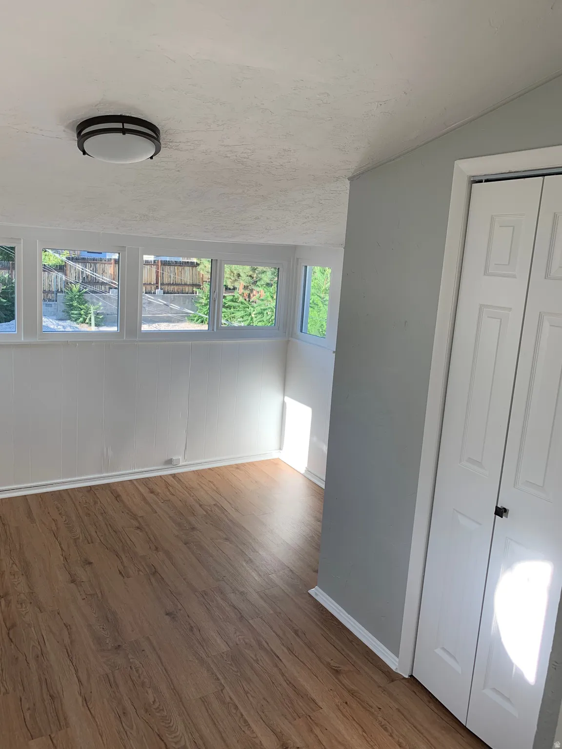 Wood-finish flooring, multiple windows, bi-fold closet doors, and recessed ceiling lighting