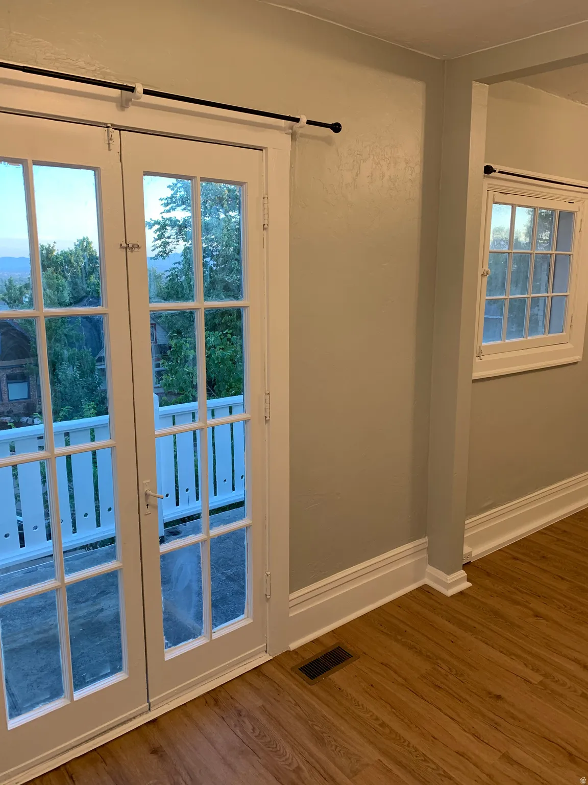 French doors with transom windows, wood-finish flooring, white trim, and light-toned walls
