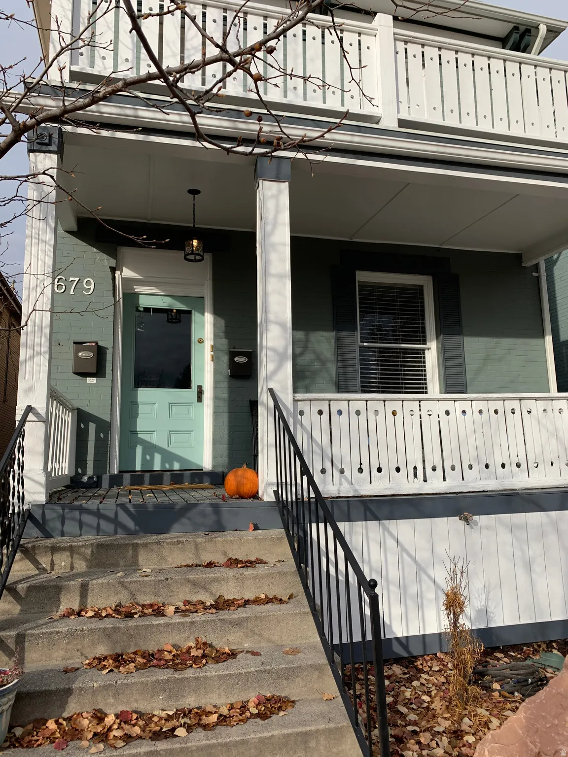 Two-story exterior with a covered porch, white railing, and a second-story balcony