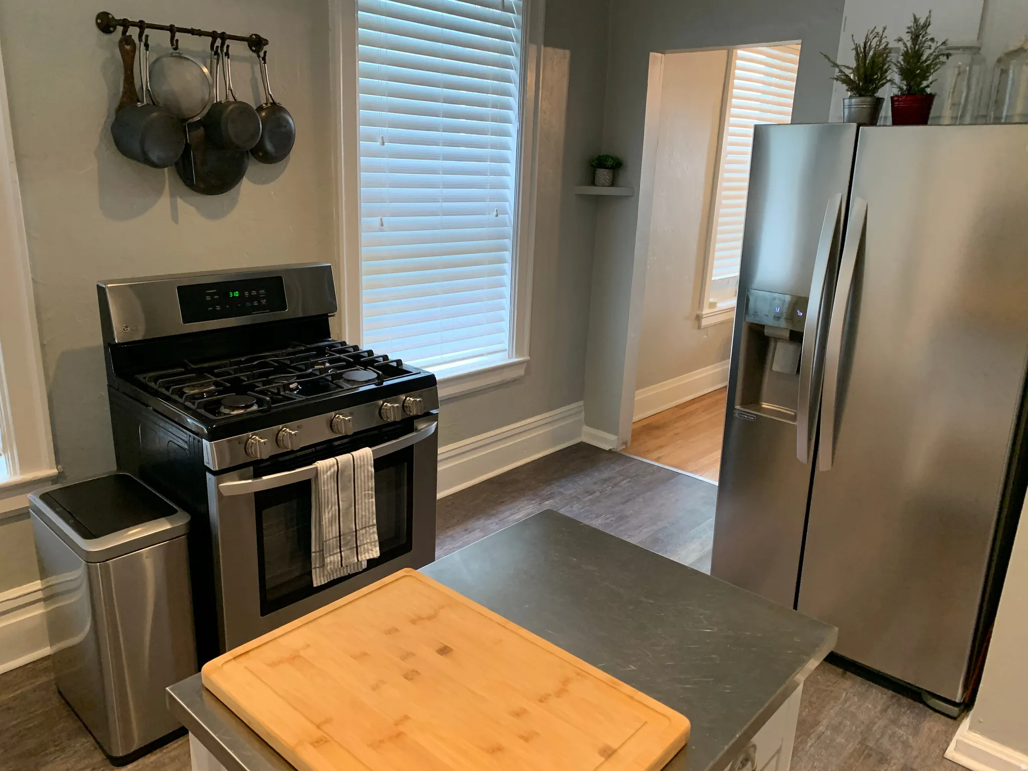 Stainless steel gas range, stainless steel refrigerator, and dark wood-finish flooring