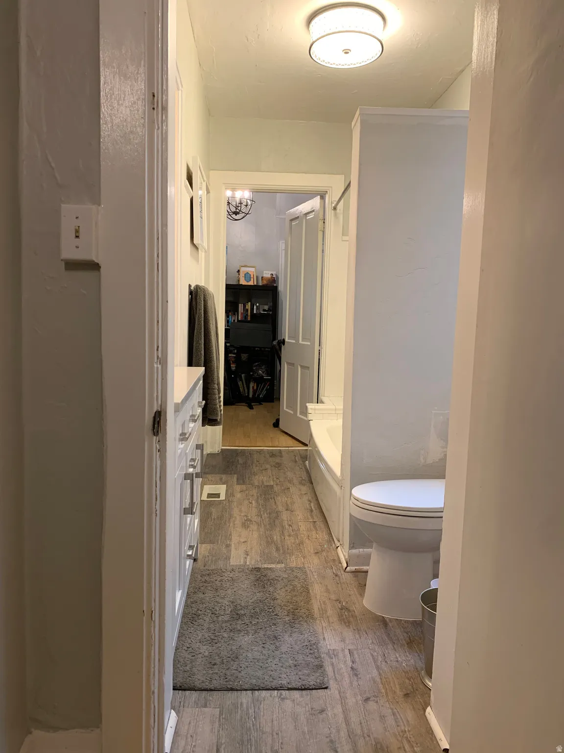 Wood-finish flooring with a white vanity featuring multiple drawers and cabinet storage