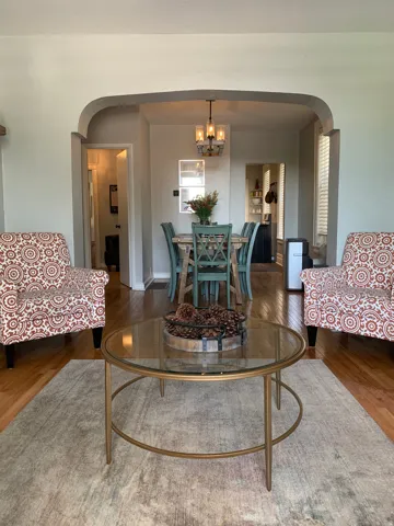 Hardwood-finish flooring throughout, featuring an arched doorway, a chandelier-style ceiling light, and light-colored walls