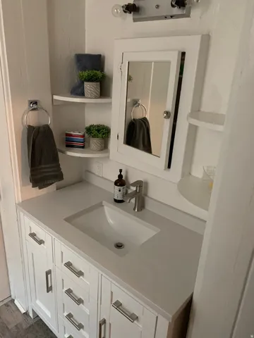 White vanity with brushed nickel hardware, integrated rectangular sink, and light-toned countertop