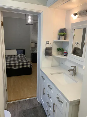 White vanity with brushed nickel hardware, integrated sink, and wall-mounted mirror