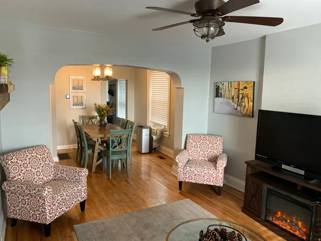 Hardwood-finish flooring, recessed archway, ceiling fan with integrated lighting, built-in fireplace, and overhead dining area lighting