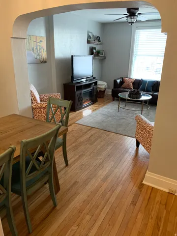 Archway opening, wood-finish flooring, ceiling fan with light fixture, window with blinds, wall-mounted shelving