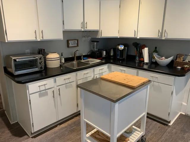 White cabinetry, black countertops, stainless steel sink, wood-finish flooring