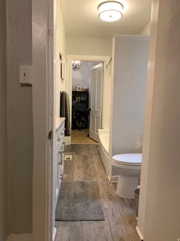 Wood-finish flooring with a white vanity featuring multiple drawers and cabinet storage