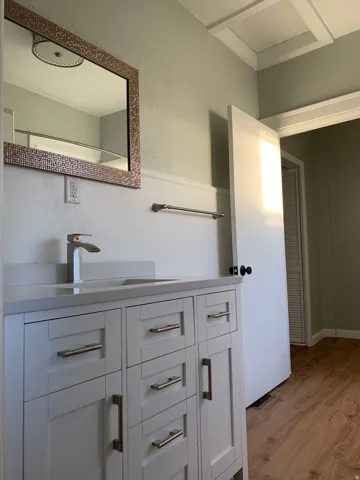 White vanity with brushed nickel hardware, grey countertop, and chrome faucet