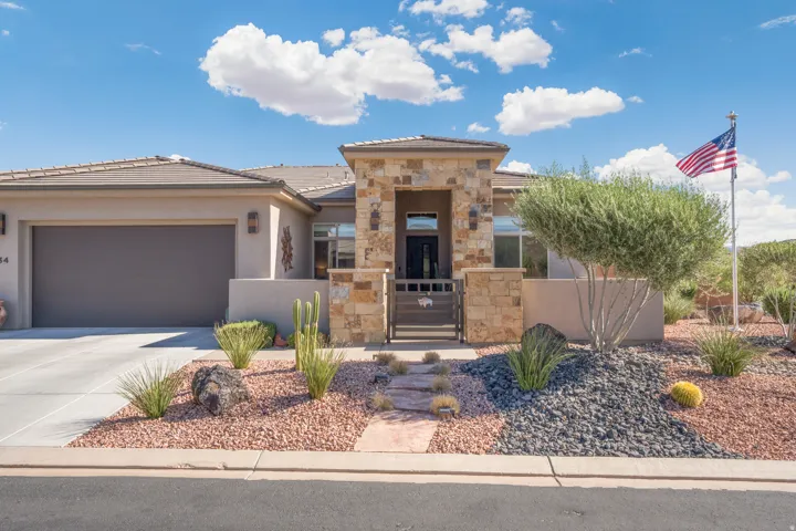 Stucco exterior with stone accents, an attached garage, and a tiled roof