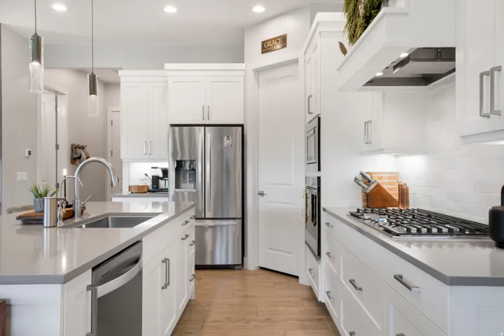 Kitchen featuring white cabinetry, stainless steel appliances, wood-finish flooring, and pendant lighting