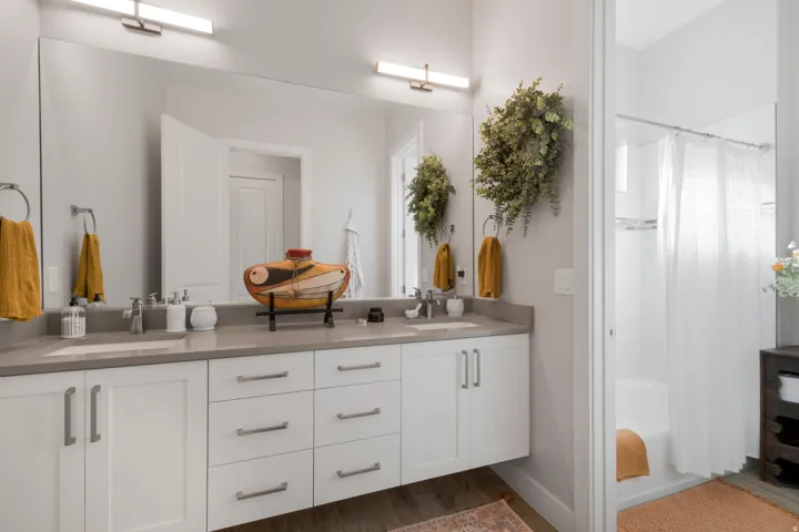 Double vanity with a light-toned countertop, dual sinks, and extensive mirrored wall