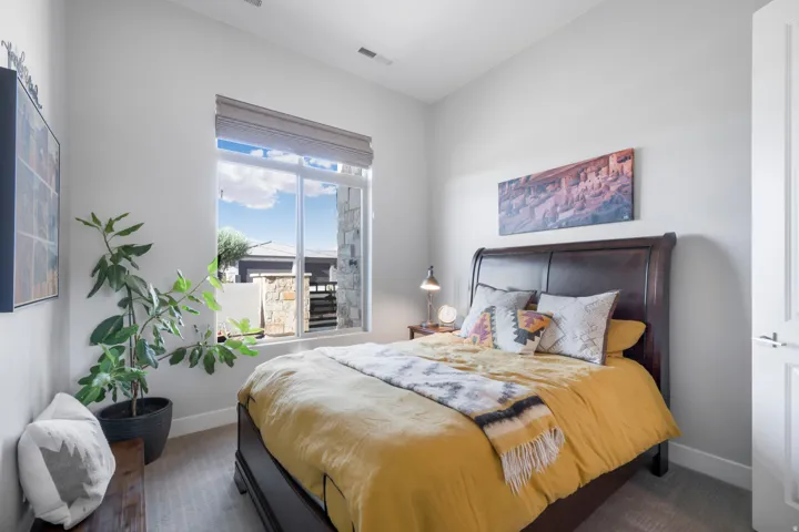 Neutral wall colors, large window with roller shade, carpeting, and overhead lighting